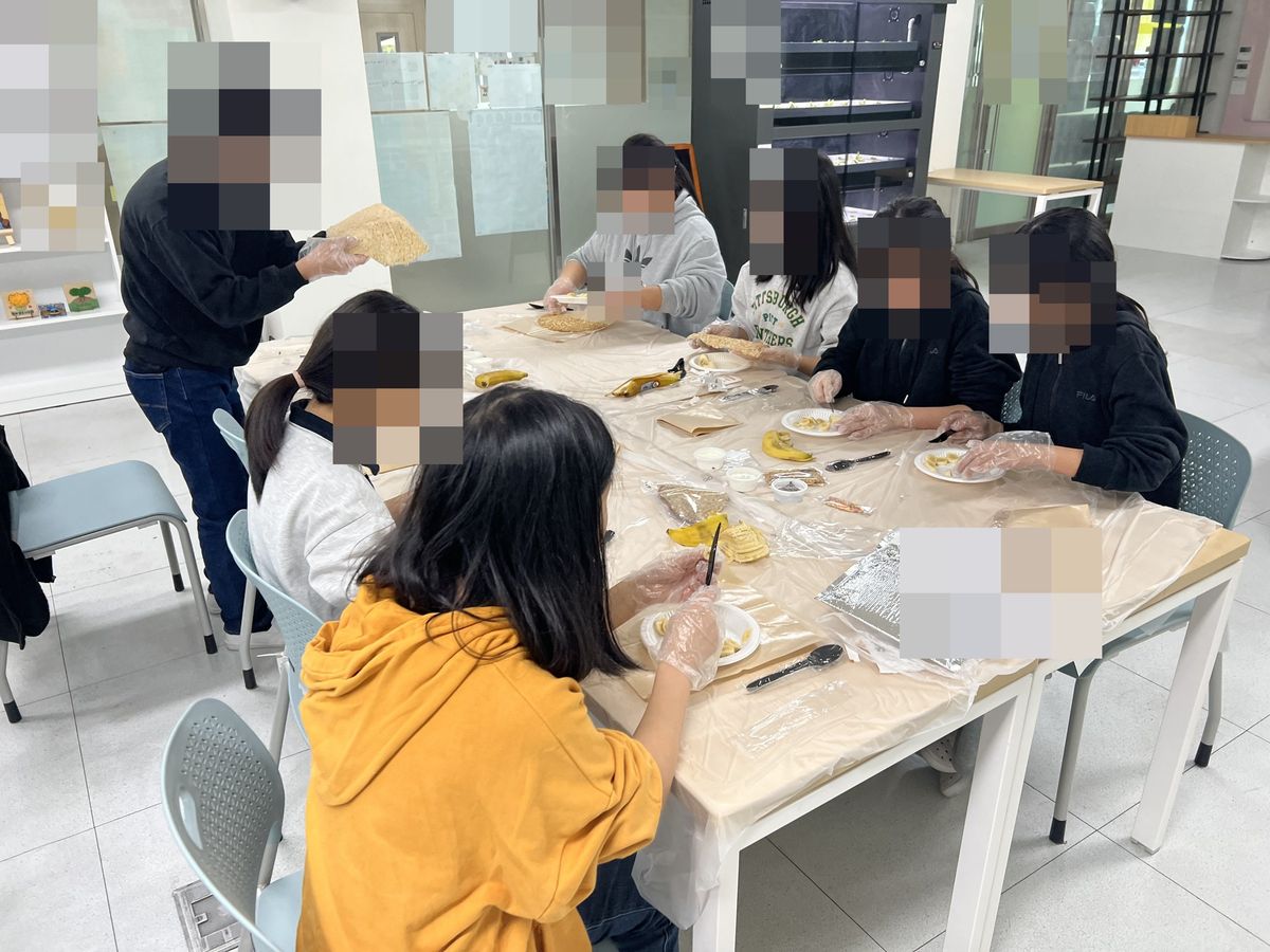 갈색 종이를 깐 모둠 책상 위 크레페 시트와 통바나나, 썬 바나나 접시