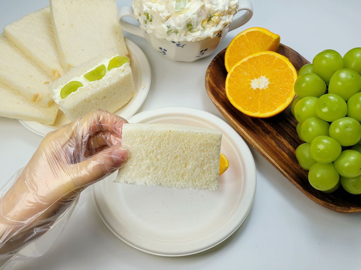 반으로 자른 식빵 한 조각을 접시 위로 들어 올린 손
