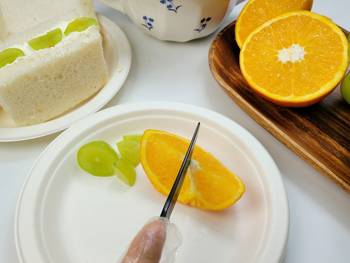 도마 대신 접시 위에서 칼로 오렌지 조각을 작게 써는 손
