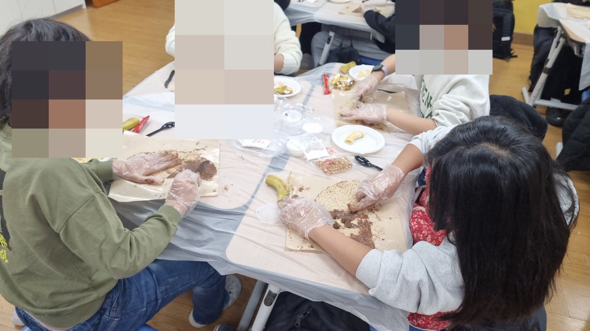 모둠 책상에 둘러앉아 비닐장갑 낀 손으로 크레페에 갈색 스프레드를 바르는 모습