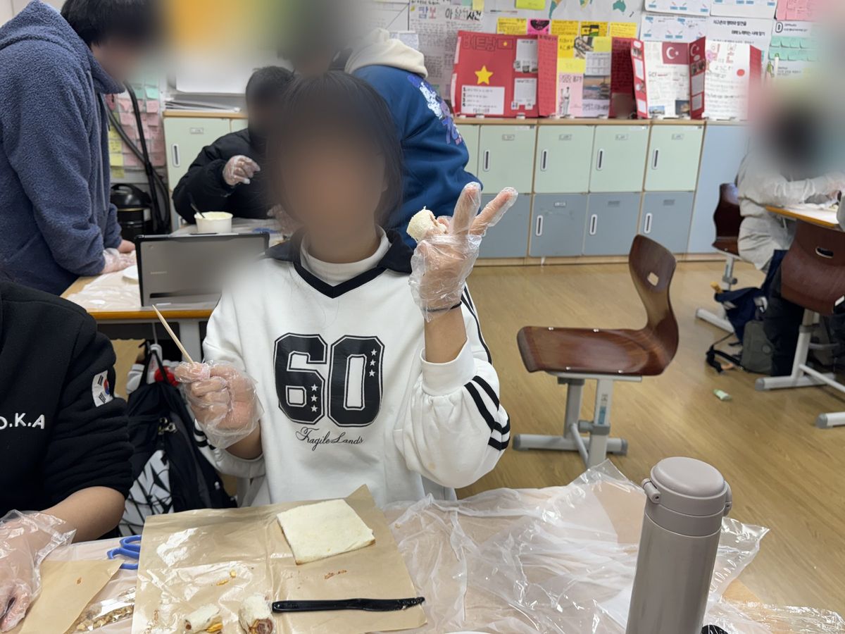 유산지 위에 납작하게 민 식빵이 놓인 책상에서 비닐장갑 낀 손이 롤 조각과 꼬챙이를 들고 있는 모습