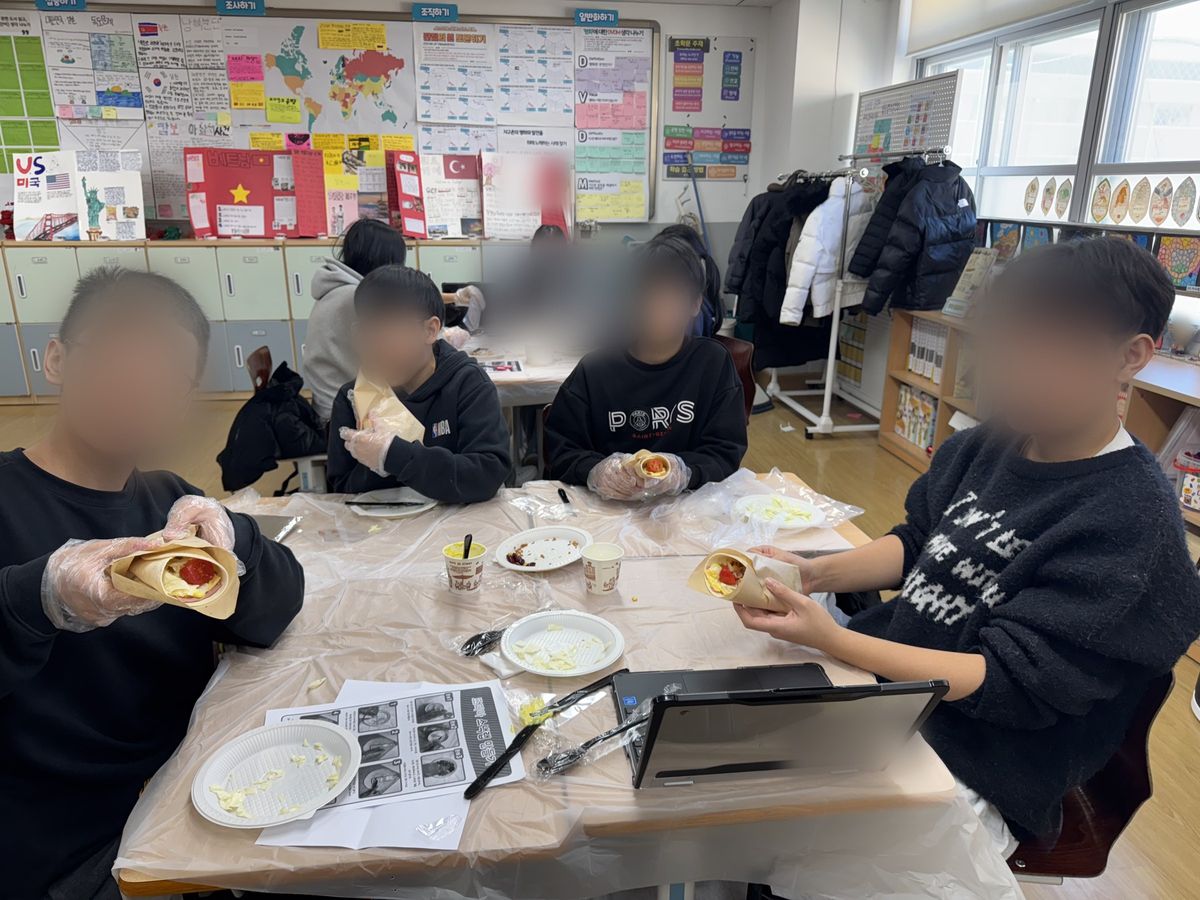 모둠 책상에 둘러앉아 유산지에 싼 또띠아 랩을 손에 들고 있는 모습