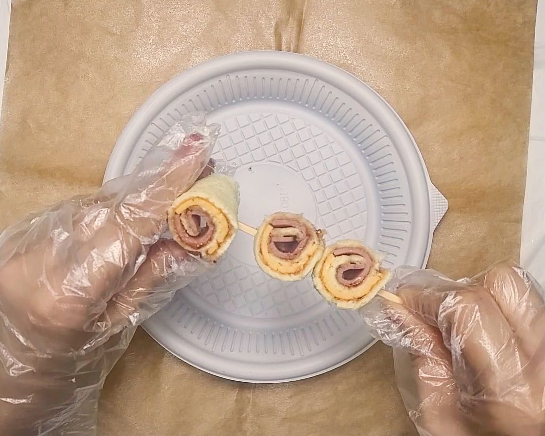 접시 위에서 롤 조각을 꼬챙이에 꽂는 손